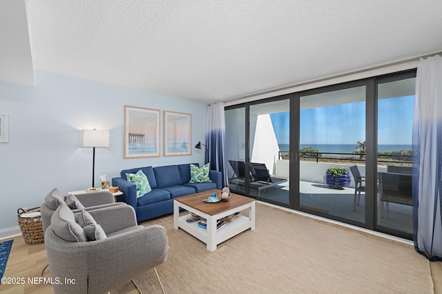 living room featuring expansive windows, a water view, a textured ceiling, and wood finished floors