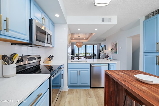 kitchen featuring visible vents, blue cabinetry, a sink, appliances with stainless steel finishes, and light wood-type flooring