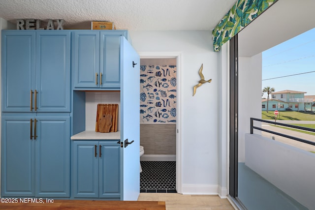 kitchen with decorative backsplash, light countertops, light wood-style floors, a textured ceiling, and blue cabinets