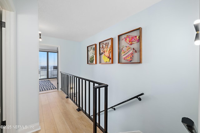 hallway with an upstairs landing and light wood-style floors