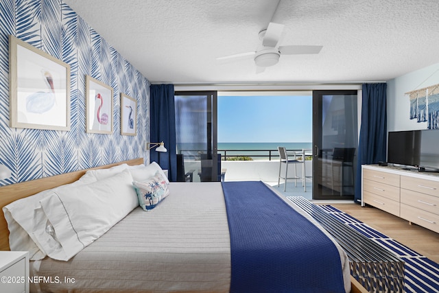 bedroom featuring wallpapered walls, ceiling fan, wood finished floors, a textured ceiling, and access to outside