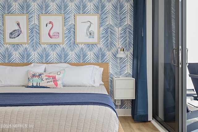 bedroom featuring wallpapered walls, wood finished floors, and baseboards