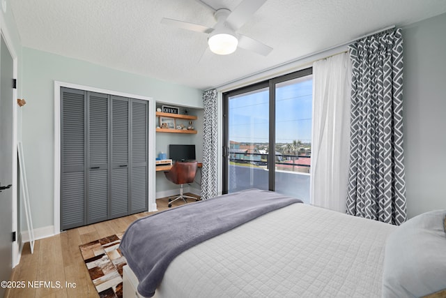 bedroom featuring a ceiling fan, a textured ceiling, wood finished floors, a closet, and baseboards