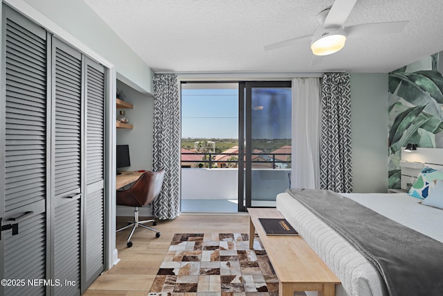 bedroom with access to outside, a textured ceiling, wood finished floors, floor to ceiling windows, and ceiling fan