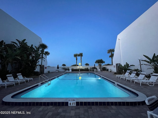 community pool with a patio area and fence