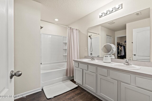 bathroom featuring visible vents, a textured ceiling, wood finished floors, and a sink