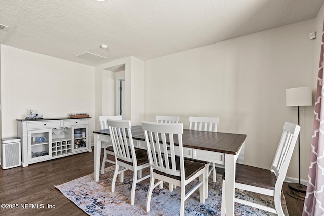 dining area with dark wood-style floors, visible vents, and a textured ceiling