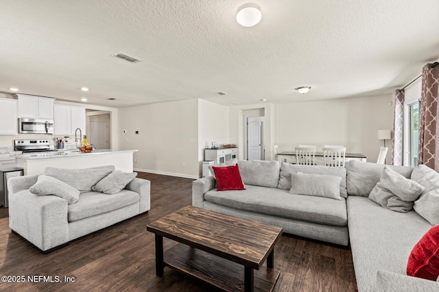 living area with recessed lighting, visible vents, a textured ceiling, and dark wood-style flooring