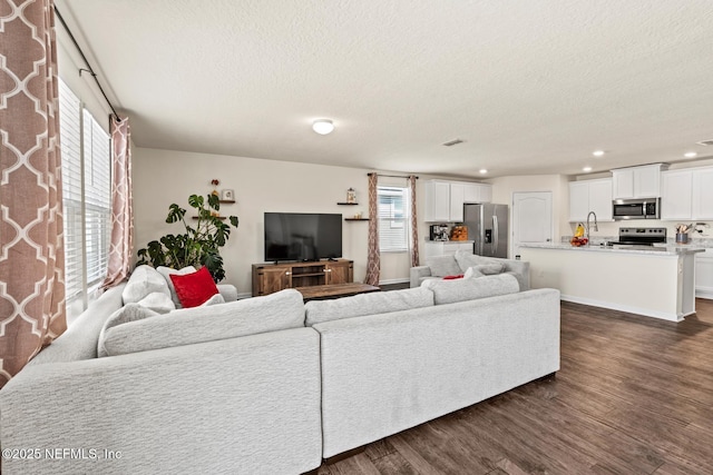 living area featuring recessed lighting, baseboards, a textured ceiling, and dark wood-style floors