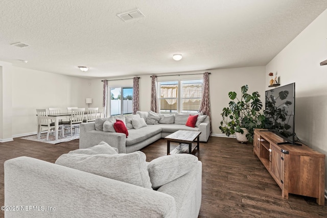 living area with dark wood-style floors, visible vents, a textured ceiling, and baseboards