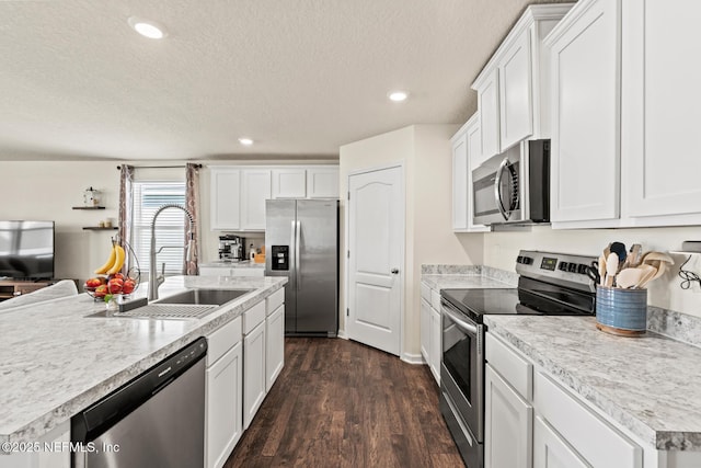 kitchen with appliances with stainless steel finishes, white cabinetry, light countertops, and a sink