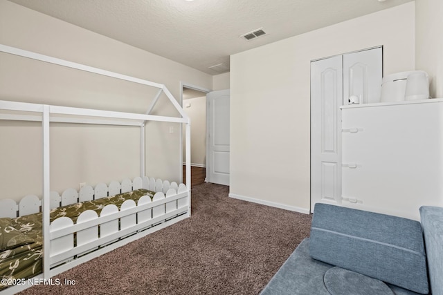 carpeted bedroom with visible vents, a textured ceiling, and baseboards