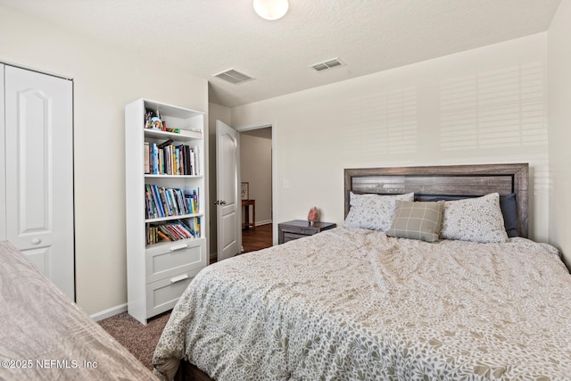 bedroom featuring baseboards, visible vents, dark carpet, and a textured ceiling