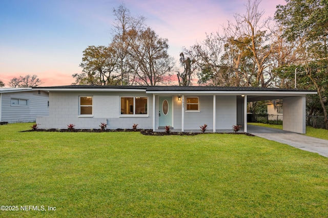 view of front of home featuring a carport, concrete block siding, concrete driveway, and a front yard