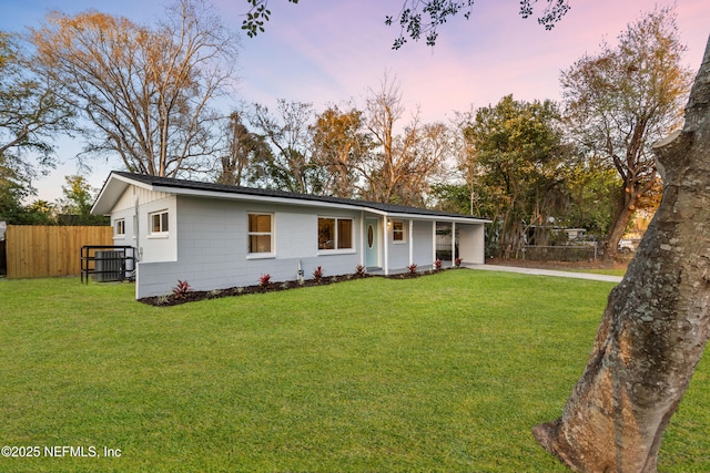 ranch-style house featuring a yard, fence, and driveway