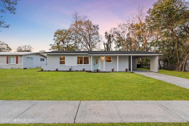 view of front of home featuring a carport, concrete driveway, and a yard