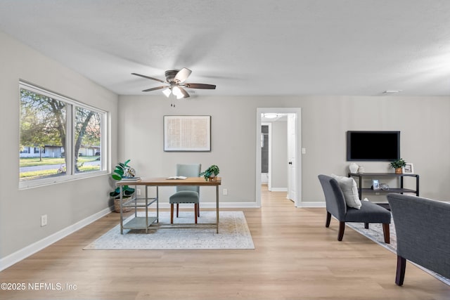 office area with a textured ceiling, light wood finished floors, and baseboards