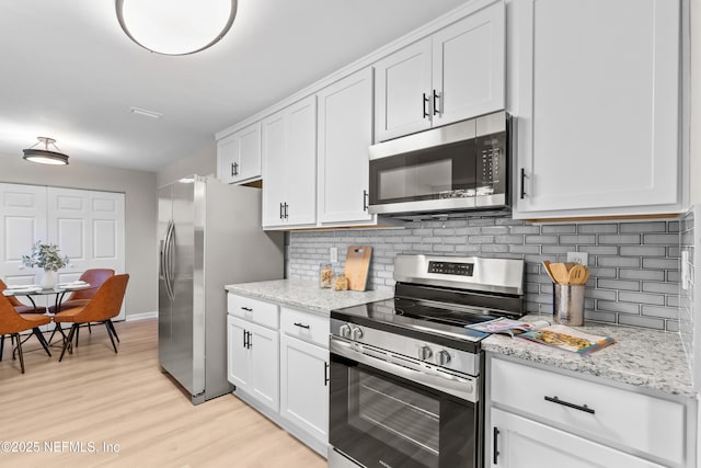 kitchen featuring white cabinets, light wood-style floors, tasteful backsplash, and stainless steel appliances