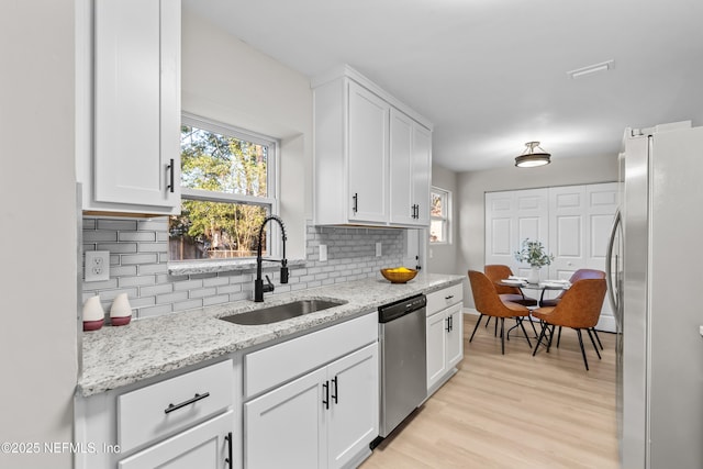 kitchen with tasteful backsplash, appliances with stainless steel finishes, white cabinets, and a sink