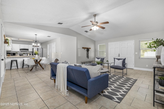 living room featuring baseboards, lofted ceiling, light tile patterned flooring, a textured ceiling, and ceiling fan with notable chandelier