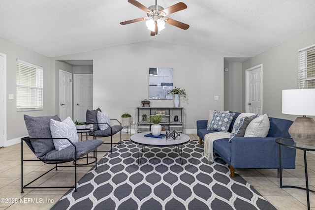 living room with lofted ceiling, light tile patterned floors, a ceiling fan, and baseboards