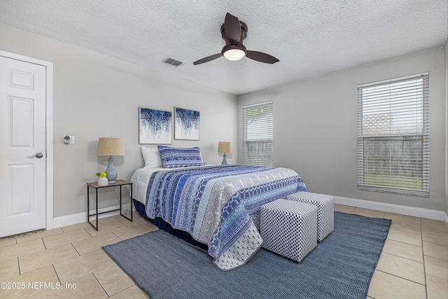 bedroom featuring light tile patterned floors, baseboards, visible vents, and a textured ceiling