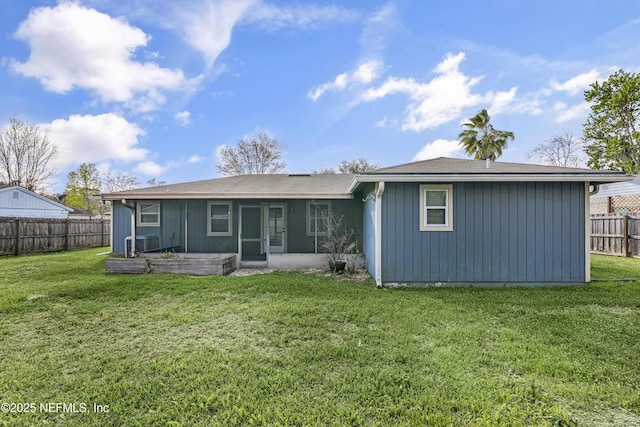 rear view of house with board and batten siding, a sunroom, central AC, a yard, and a fenced backyard