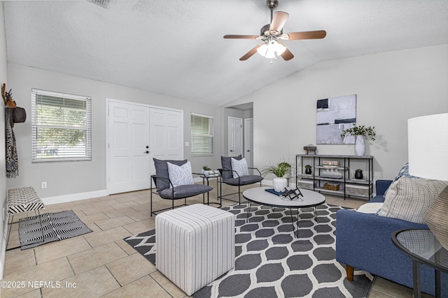 living room with lofted ceiling, a textured ceiling, tile patterned flooring, baseboards, and ceiling fan