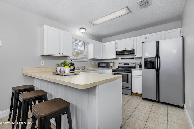 kitchen with visible vents, under cabinet range hood, light countertops, appliances with stainless steel finishes, and a peninsula