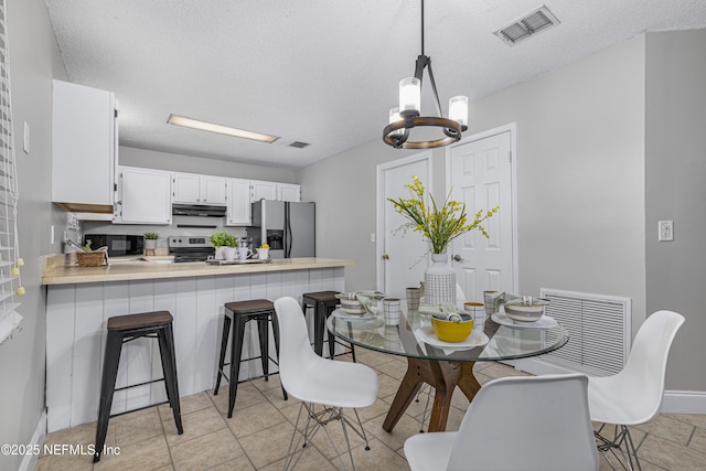 dining space featuring a notable chandelier, baseboards, visible vents, and a textured ceiling