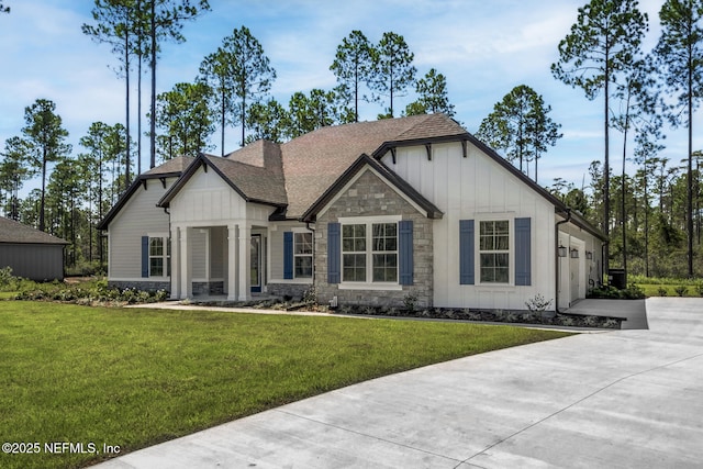 view of front of house featuring a garage, driveway, stone siding, a front lawn, and board and batten siding