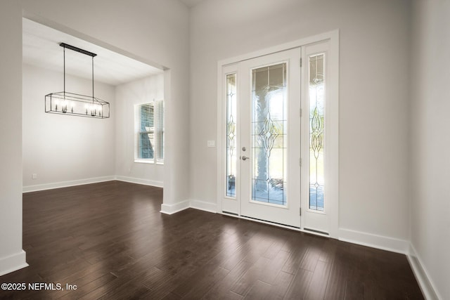 foyer featuring an inviting chandelier, baseboards, and dark wood finished floors