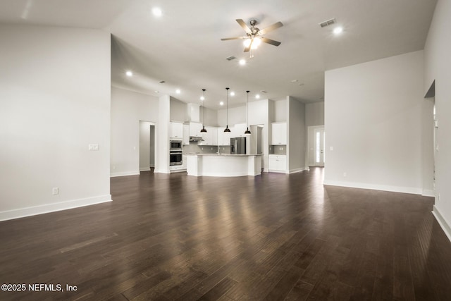 unfurnished living room with ceiling fan, dark wood-type flooring, visible vents, and baseboards