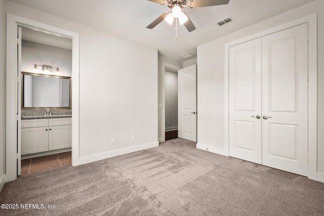 unfurnished bedroom with connected bathroom, visible vents, a sink, and carpet flooring