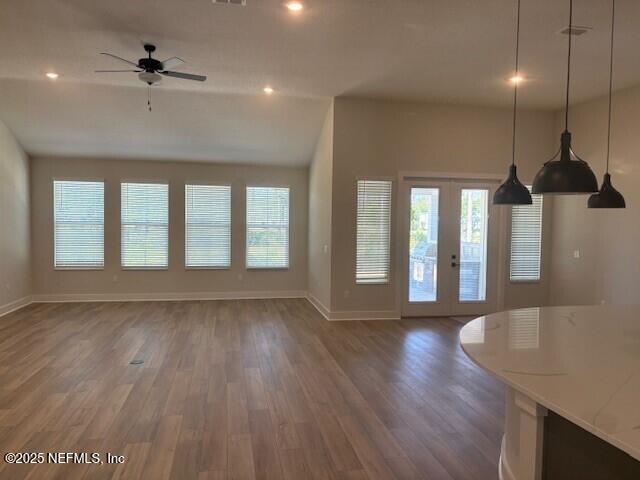unfurnished living room featuring plenty of natural light, baseboards, and wood finished floors