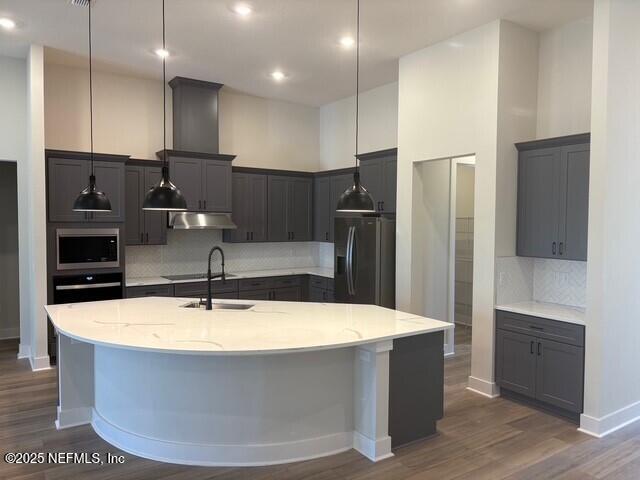 kitchen featuring dark wood finished floors, decorative backsplash, a sink, and black appliances