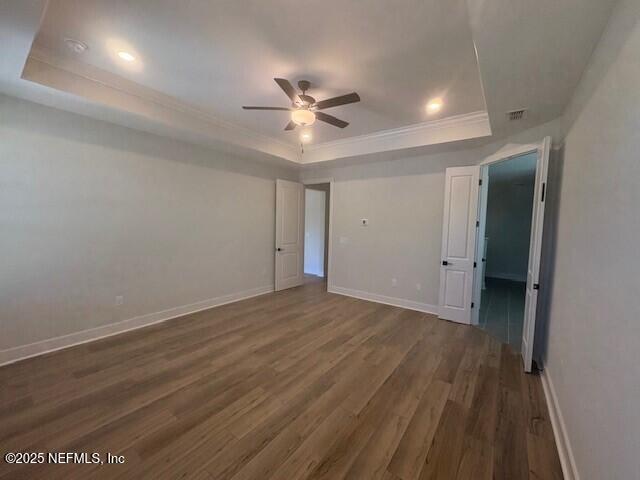 unfurnished bedroom with baseboards, ornamental molding, wood finished floors, and a raised ceiling