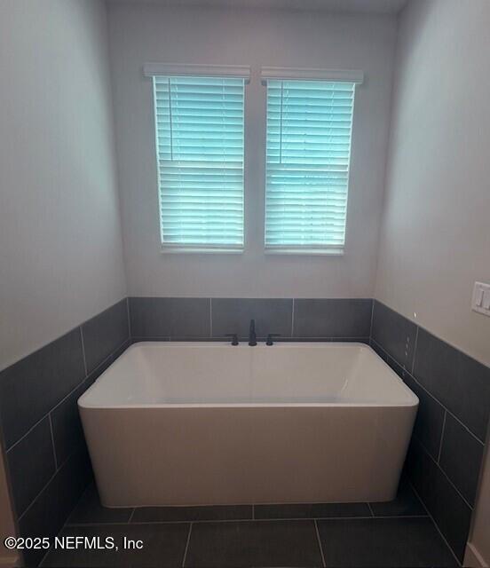 bathroom with a freestanding tub, tile patterned floors, and tile walls