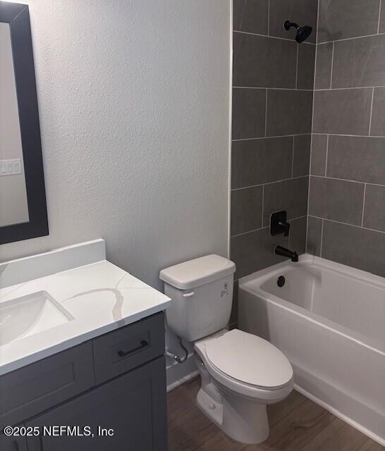 full bath with vanity, wood finished floors, bathtub / shower combination, and toilet