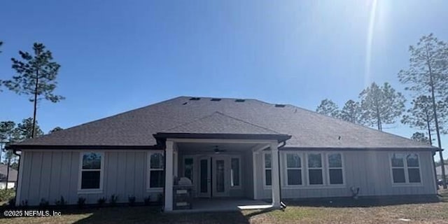 back of property with a ceiling fan, board and batten siding, and a patio area