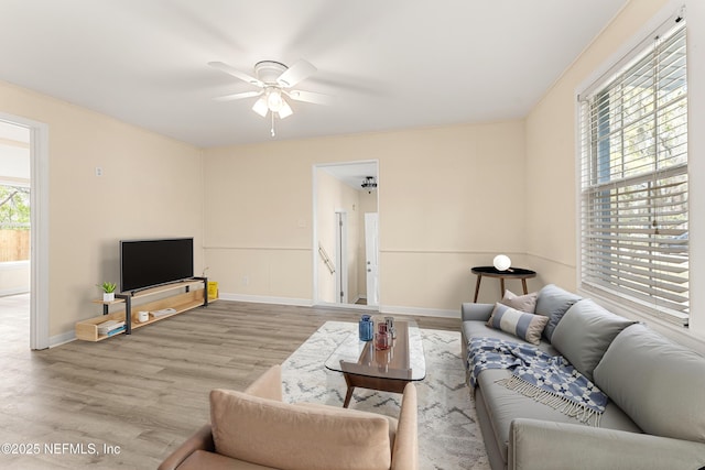 living area with light wood-style flooring, baseboards, and ceiling fan