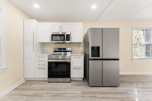 kitchen with baseboards, white cabinets, light wood-style flooring, stainless steel appliances, and light countertops