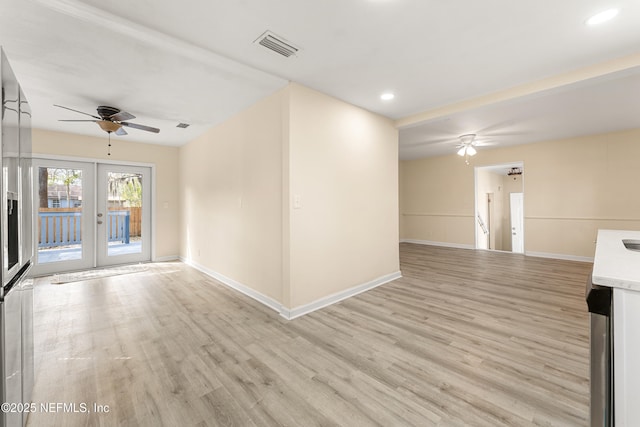 spare room featuring french doors, visible vents, light wood-style flooring, a ceiling fan, and baseboards