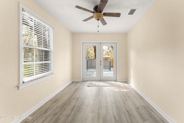 empty room featuring baseboards, visible vents, wood finished floors, and french doors