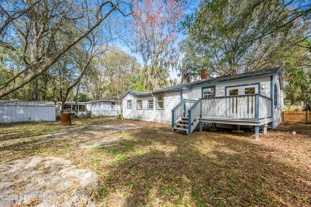 rear view of property with a chimney, fence, and a wooden deck