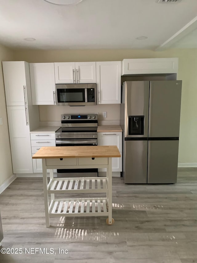 1256 Woodruff Ave, Jacksonville, FL 32205 - kitchen featuring wood counters, appliances with stainless steel finishes, baseboards, and white cabinetry