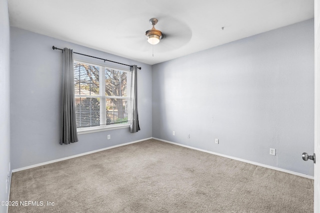 carpeted spare room featuring baseboards and ceiling fan