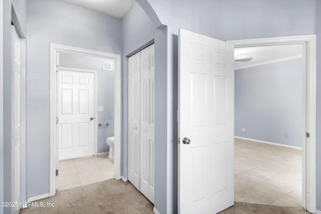 corridor with tile patterned floors, carpet flooring, arched walkways, and baseboards