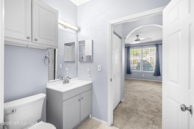 bathroom featuring baseboards, vanity, toilet, and a ceiling fan