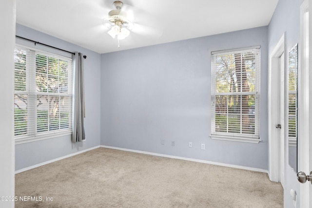 carpeted empty room with ceiling fan and baseboards